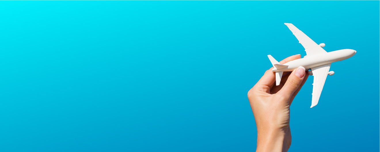 Hand holding a white model airplane against a blue background