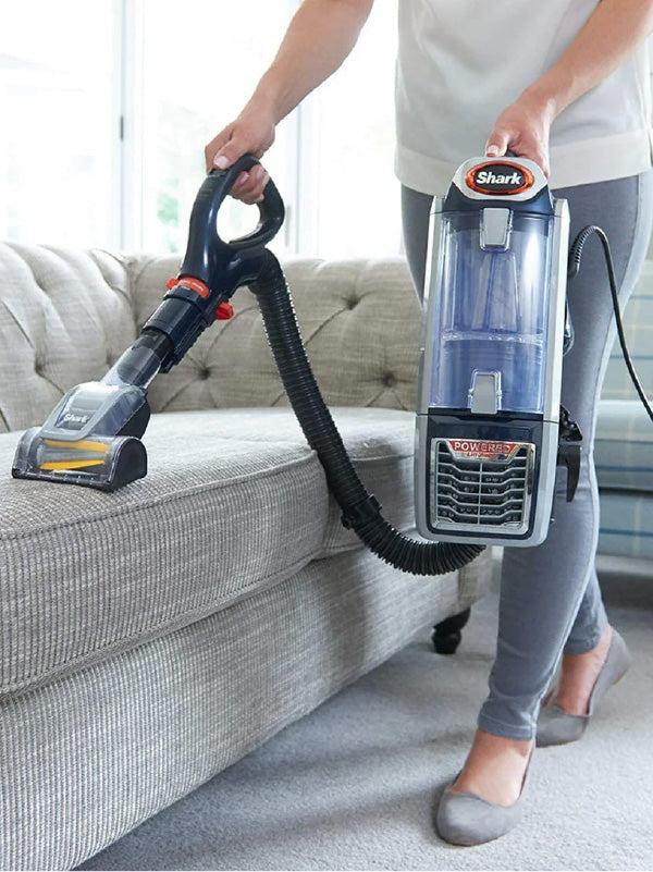 Person using a Shark vacuum cleaner on a sofa