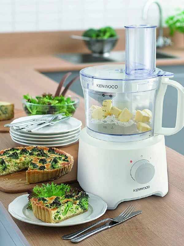 Kenwood food processor on a kitchen counter with food and utensils around