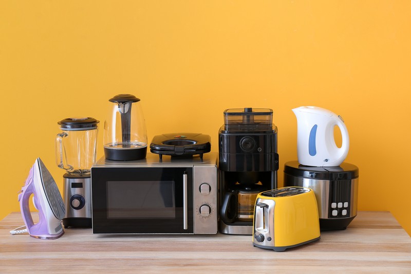 Collection of kitchen appliances on a wooden surface with a yellow background