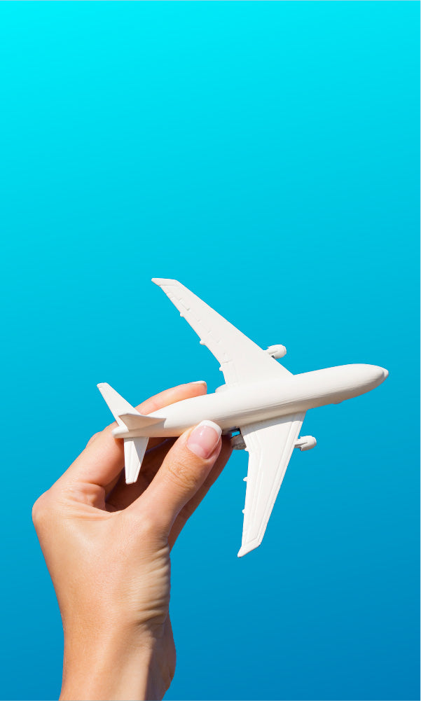 Hand holding a white model airplane against a blue background